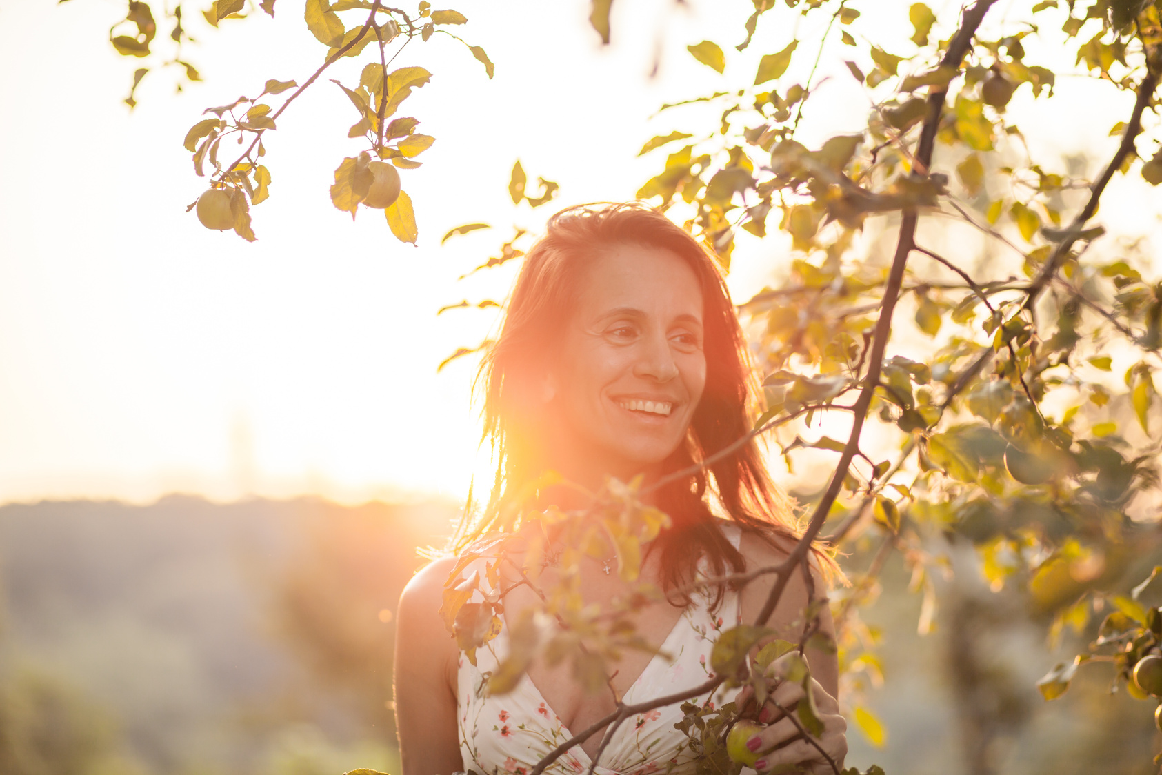 Portrait of smiling, confident mature woman standing along apple tree